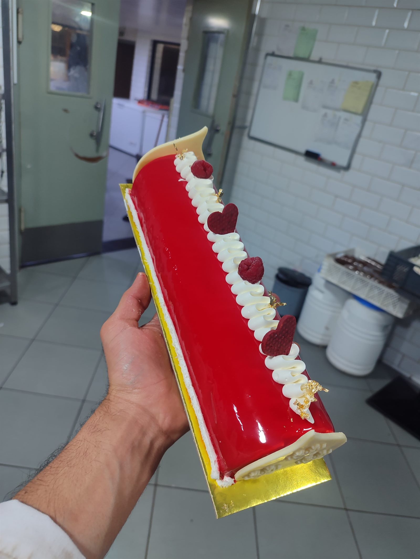 Himbeerrolle mit roter Glasur und Sahnedekor